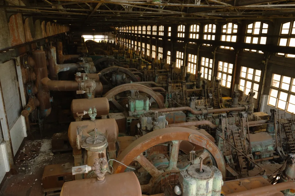 A row of rusty machines abandoned in an old steel factory.