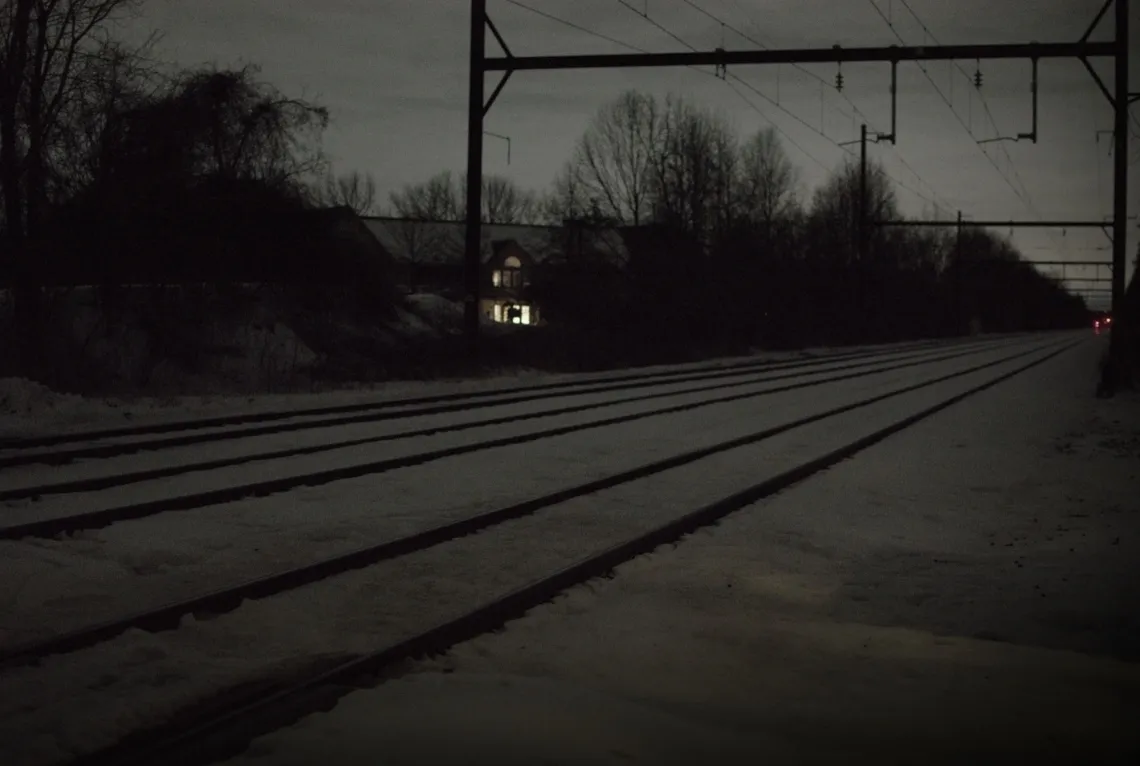 Railroad tracks on a snowy ground, leading from the left foreground to the right background.