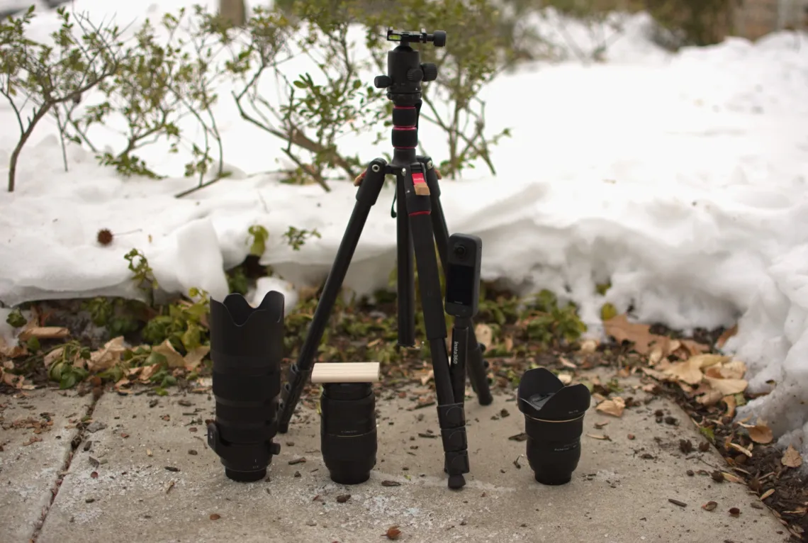 Three camera lenses, a 360 camera connected to a selfie stick, and a standing tripod marked with bandages.
