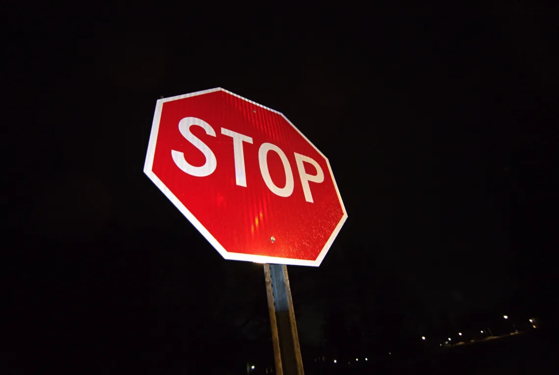 A bright red stop sign covered in rain at night.