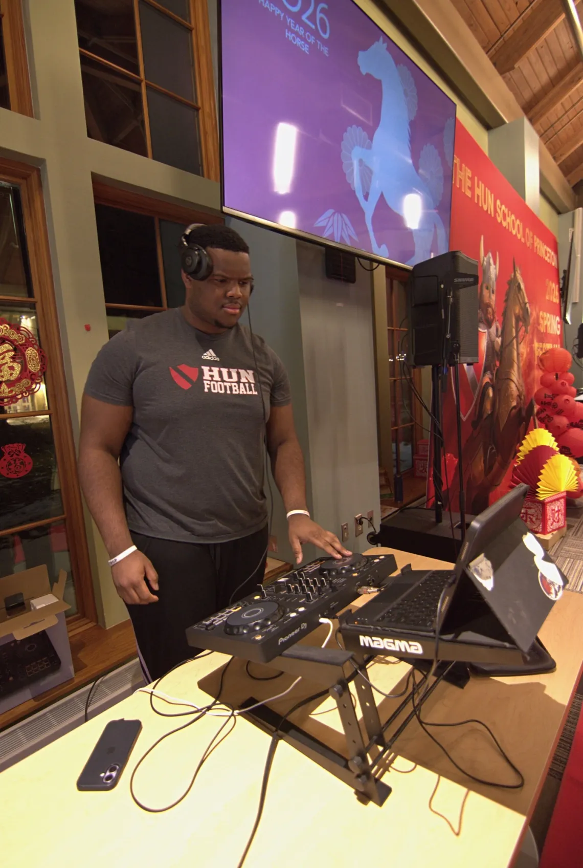 Hun Football student programs and mixes the music at a DJ station.