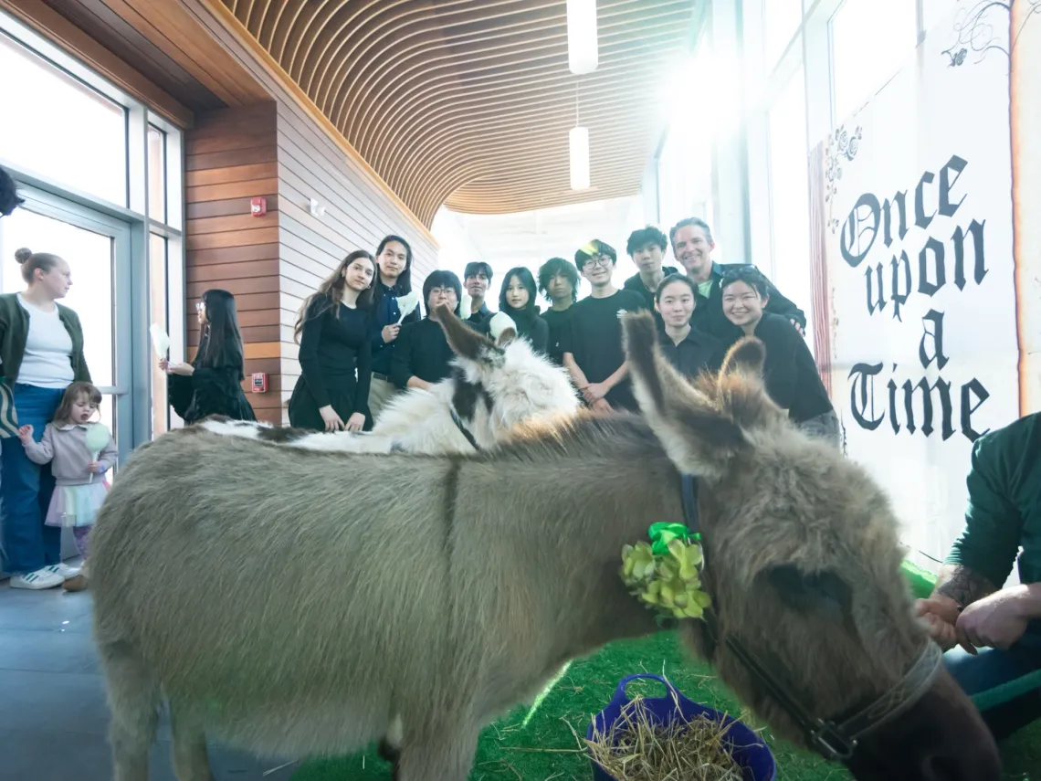 Brown donkey stands in front of a group of musicians, all in black attire.