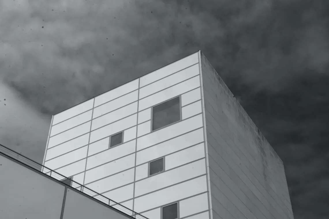 A square building faces the sky, with dots of grime (top-left) stuck to the camera sensor and lens.