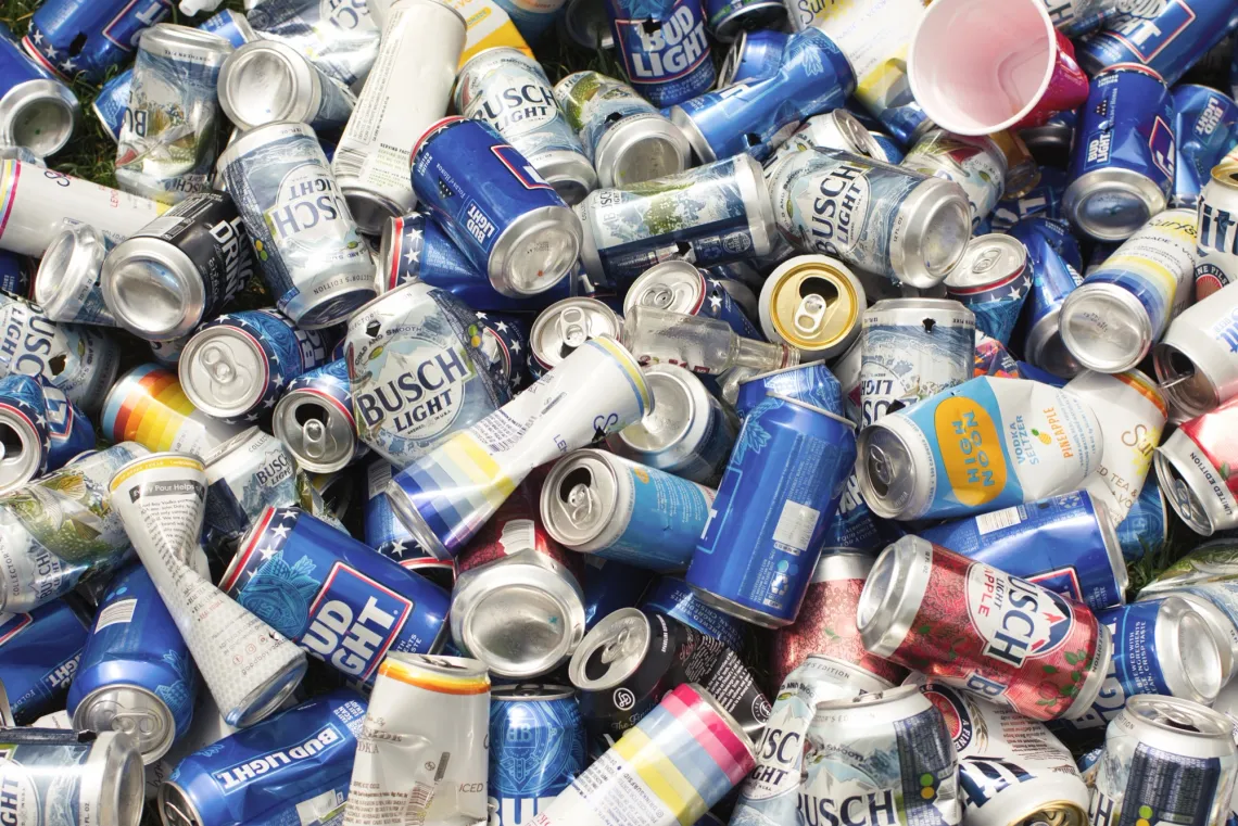Various empty cans of alcoholic drinks are piled on top of each other as trash.