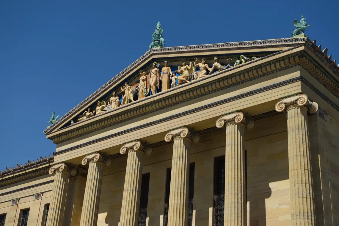 Triangular pediment sits above classical Greek architecture, with polychrome mythological figures depicted.