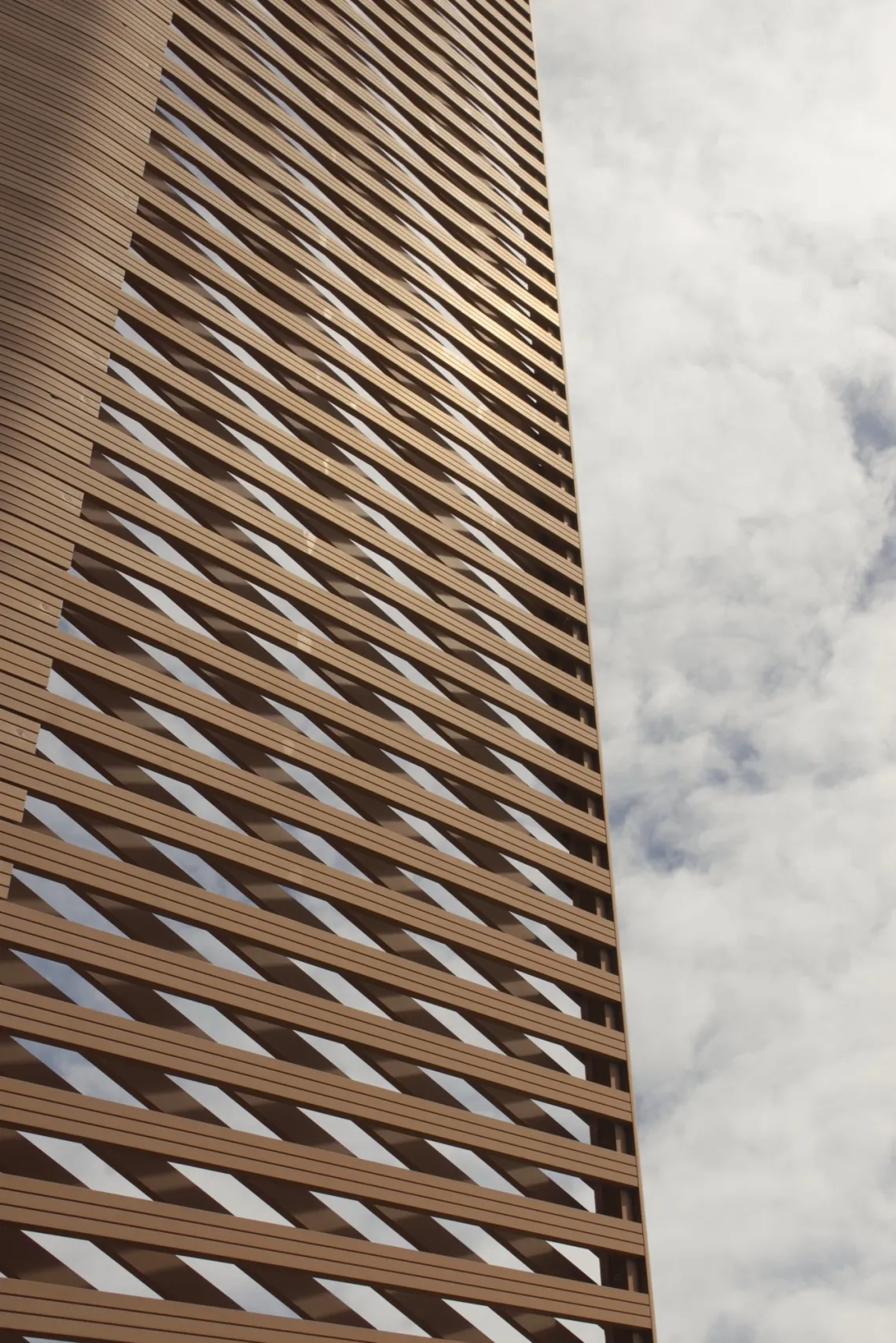 Strips of metal are constructed to form a pattern in front of the cloudy sky.