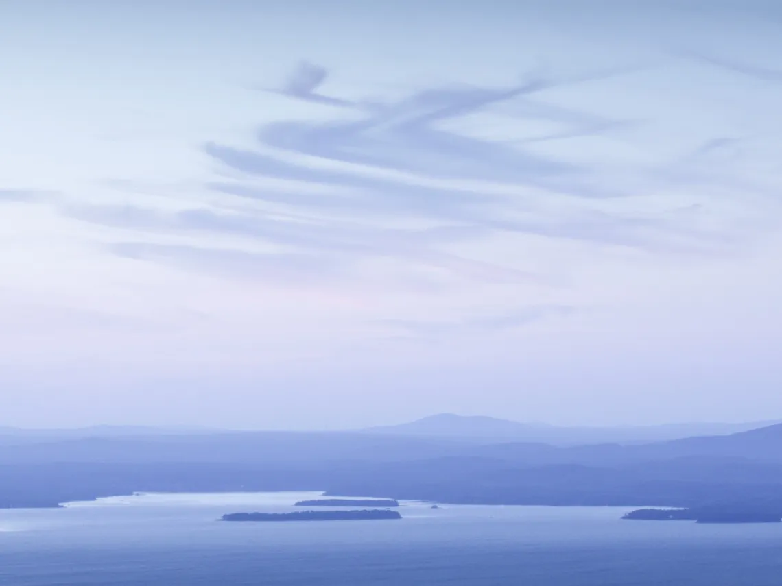 Landscape shot of a body of water with wispy clouds overhead. The entire image is covered in blue haze after a sunset.