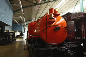 A bright orange train is on display at a railroad museum.