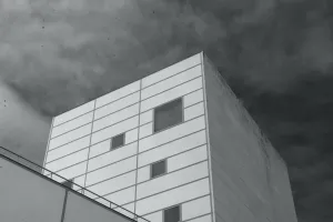 A square building faces the sky, with dots of grime (top-left) stuck to the camera sensor and lens.